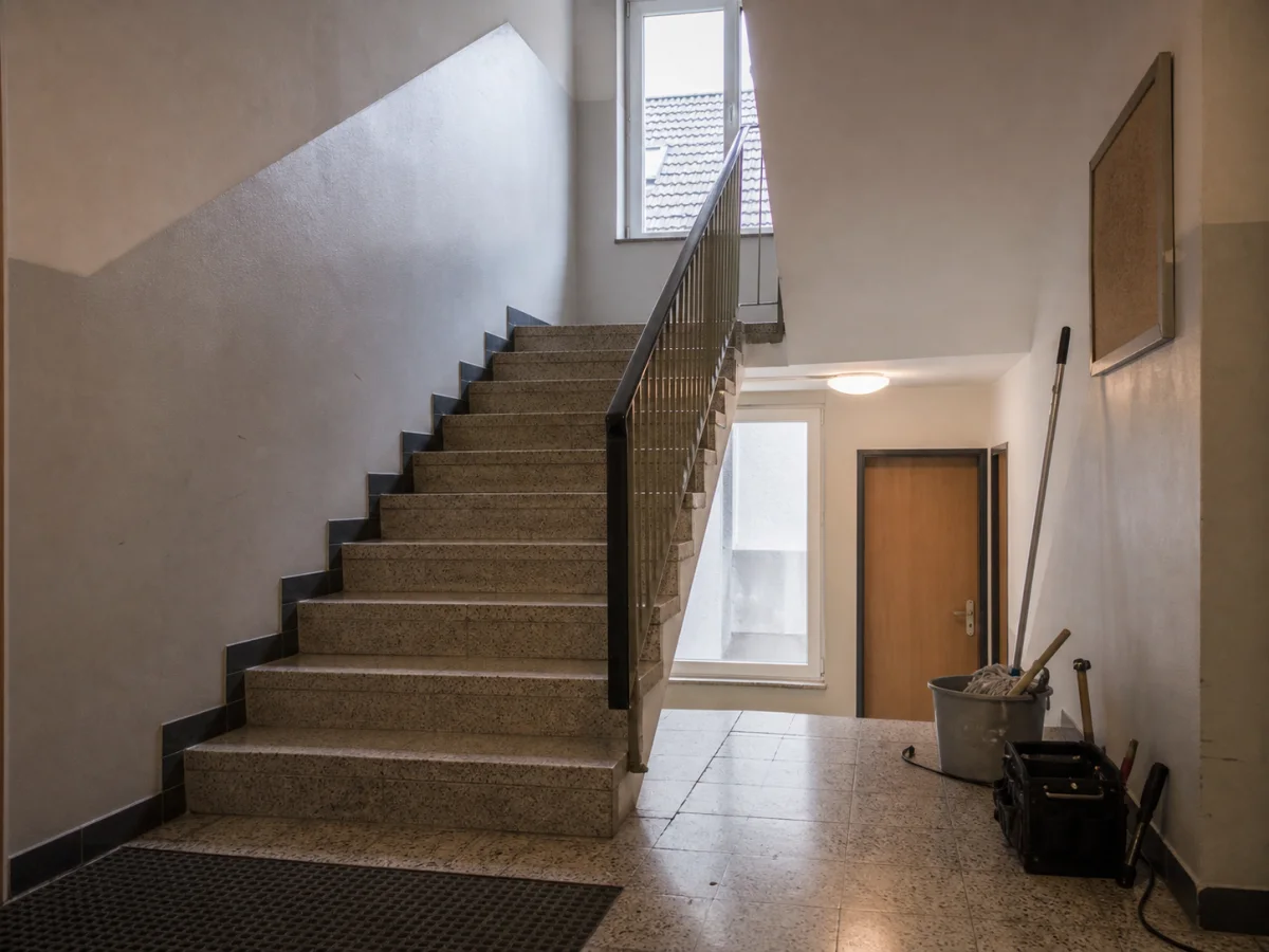 Treppenhaus eines Mehrfamilienhauses mit Terrazzoboden und Reinigungsgerät am Rand